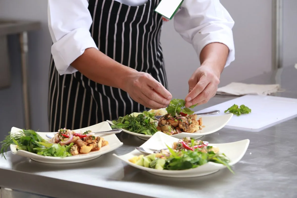 Chef che impiatta piatti gourmet con verdure fresche in cucina professionale