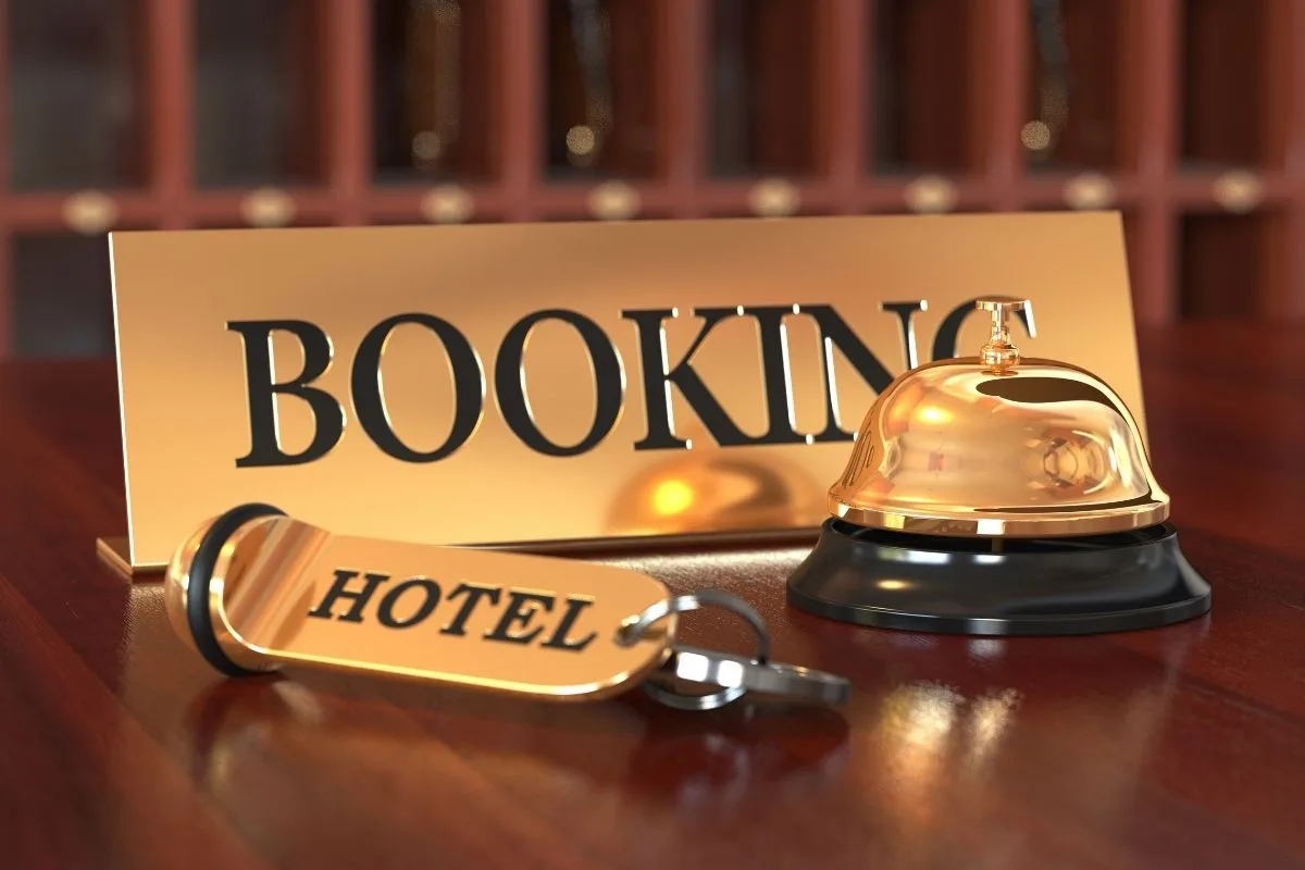 Campanello dorato da reception con targhetta Booking e chiave della camera d'hotel