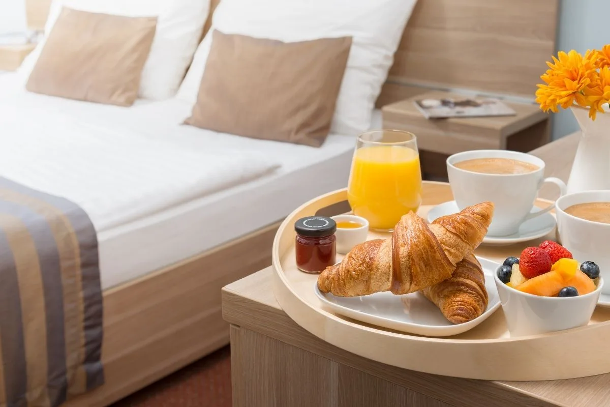Colazione in camera con cornetti, spremuta d'arancia, caffè e frutta fresca vicino al letto