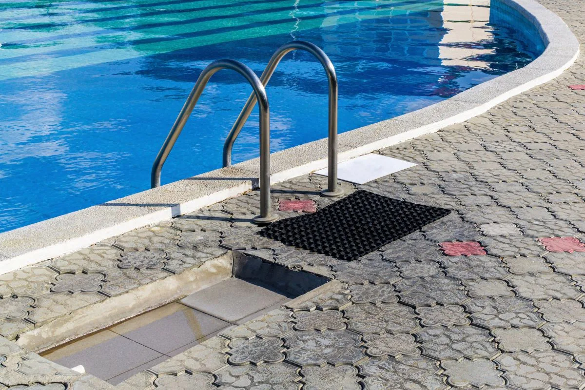 Bordo piscina con scaletta in acciaio e pavimentazione decorata